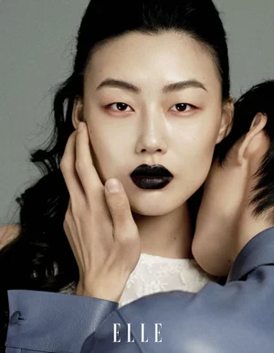 Close-up portrait of an East Asian woman with dark lipstick, being embraced by a man in a blue shirt for Elle China by Dalong Yang.