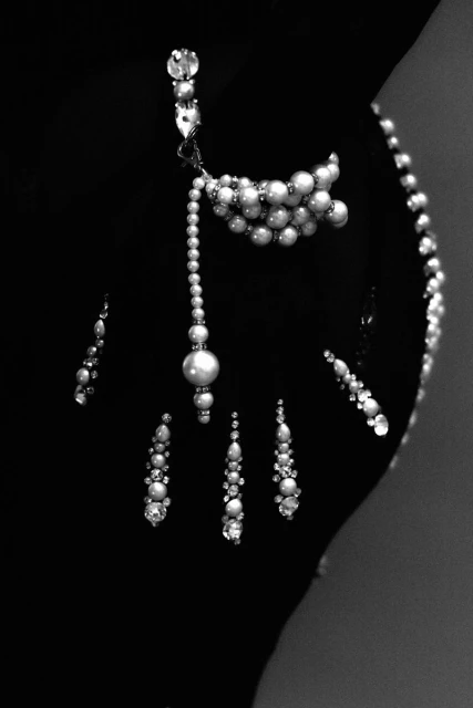 Elegant pearl jewelry set featuring a necklace, earrings, and embellishments, displayed against a dark backdrop in a studio setting.