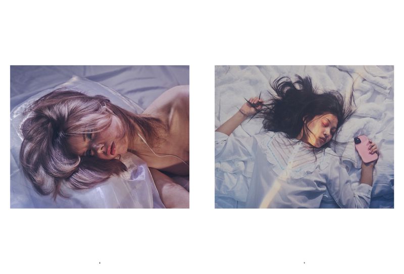 Two women lie in bed, seen in adjacent frames. Both are fair-skinned with dark hair and are using their cell phones while resting.