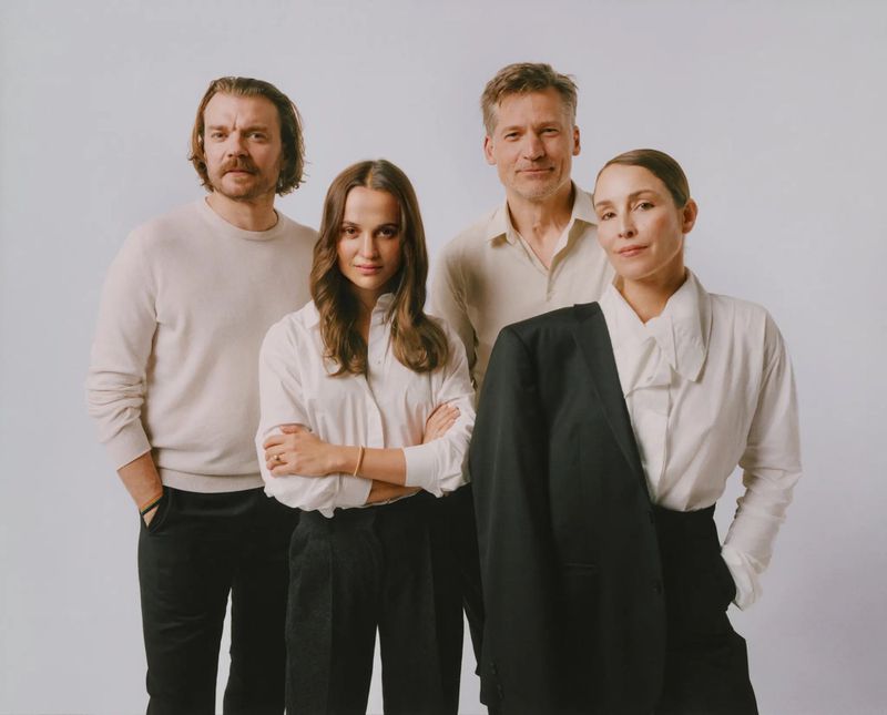 Studio shot of four adults in coordinated black and white outfits posing against a neutral background for a fashion-inspired portrait.
