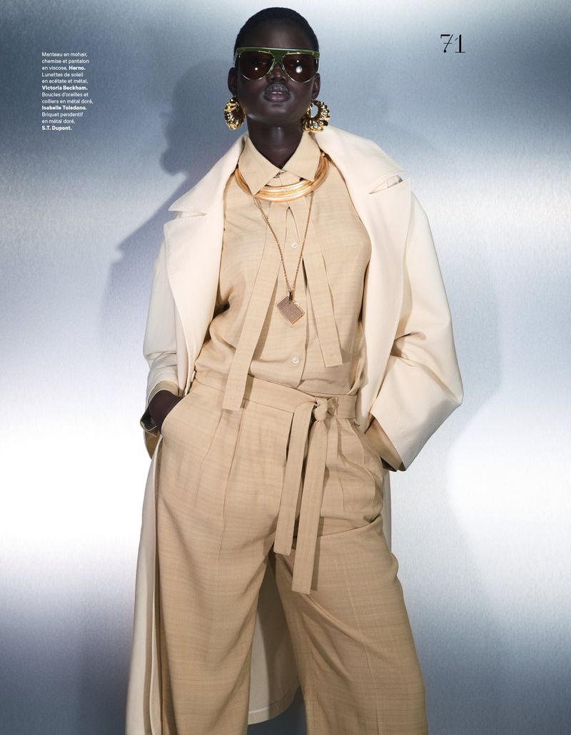 Model Nyakong Chan wearing tan trousers, a beige shirt, and a white coat with sunglasses in an editorial for Les Echos.