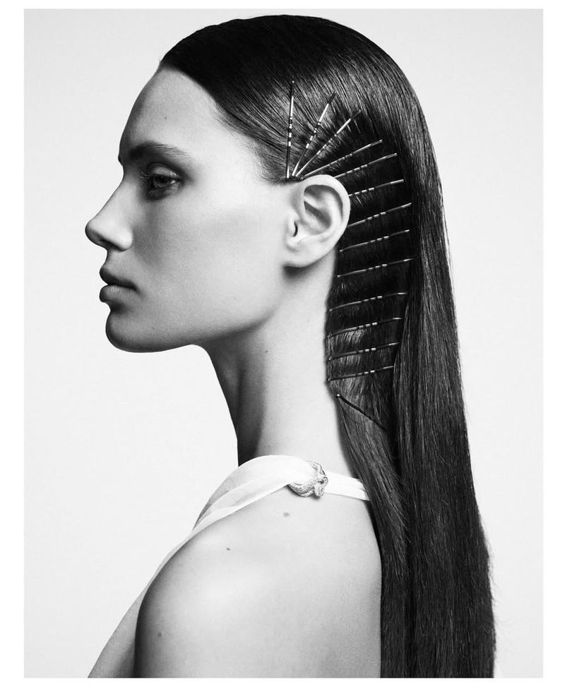 Black and white portrait of a woman with straight dark hair styled with bobby pins on a white background in a photo studio.