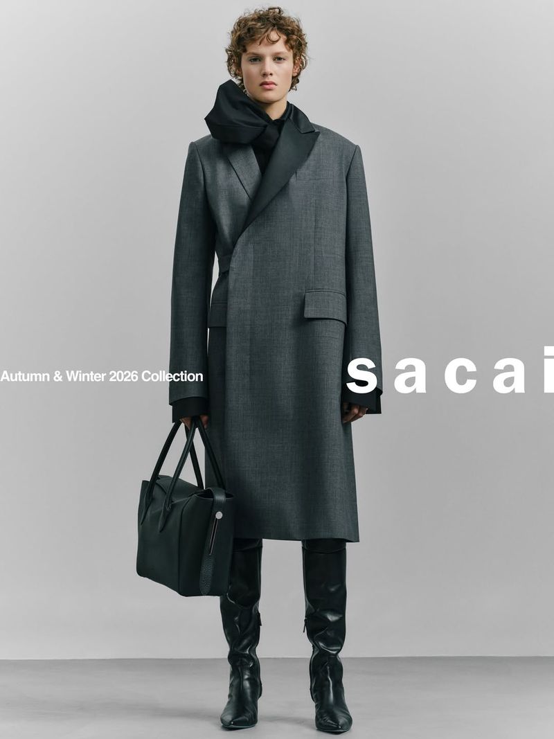Fashion shot: Woman in grey overcoat, scarf, black boots, holding bag in studio. Autumn/Winter 2026 Collection. Sacai branding visible.