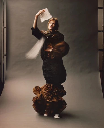 Model in layered textured garments tossing a white cloth in a studio setting captured by Jamie Hawkesworth for Self Service.