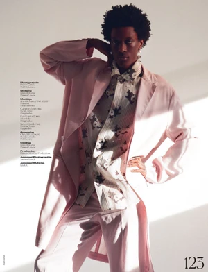 Model in pink blazer and patterned shirt posing against a plain background with editorial lighting