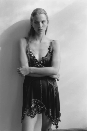 Monochrome portrait of model Rebecca Leigh Longendyke in a sequined dress against a pale wall for Self Service.