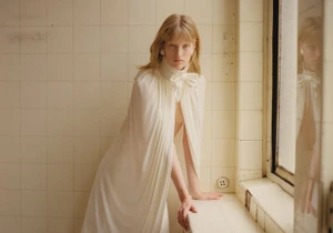 Model in white pussy-bow blouse leaning against tiled wall by window for Self Service N 64 editorial by Juliette Abitbol