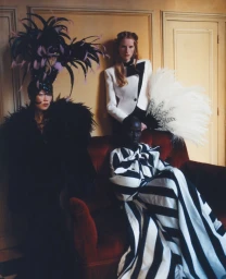 Four models pose in haute couture monochrome fashion, featuring feathered headpieces and dramatic black and white gowns.