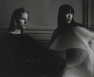 Two female models in dark attire posed indoors for a Vogue Polska couture fashion editorial photographed by Antonino Cafiero.