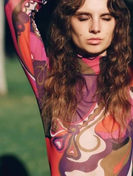 Model Giselle Norman wearing a colourful patterned mesh top with eyes closed outdoors in the Winter Sun project for Net-A-Porter.