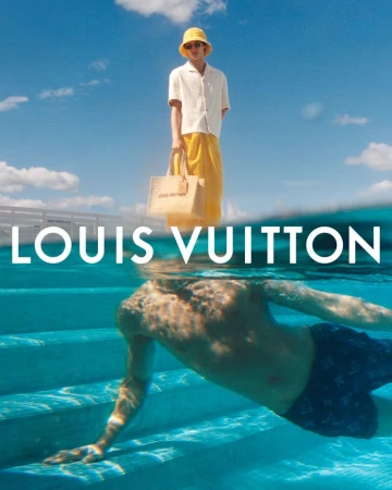 Fashion shoot with a man above water holding a tote bag and a swimmer below water, with a bright blue sky and turquoise water.