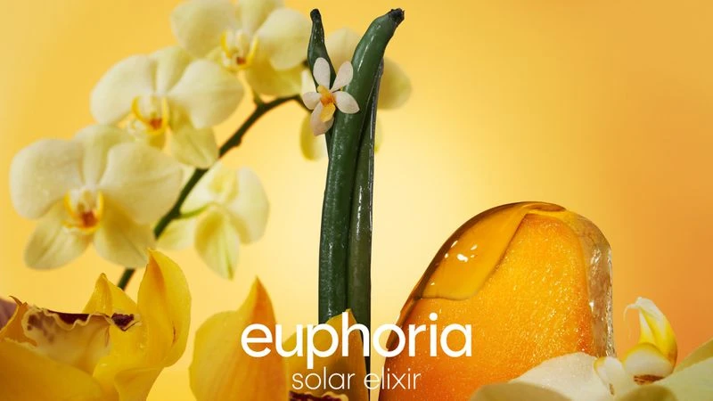 Still life shot of orchids and a fragrance bottle with the text 'euphoria solar elixir' against a yellow background.