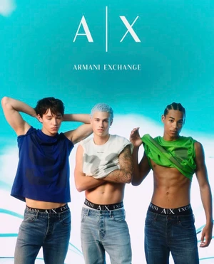 Three male models posing in jeans and branded underwear against a bright turquoise and white studio background