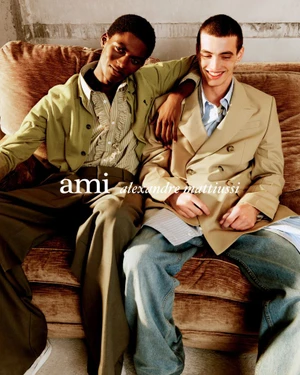 Two male models seated on a brown sofa for the Ami S/S 2026 campaign photographed by Anthony Seklaoui
