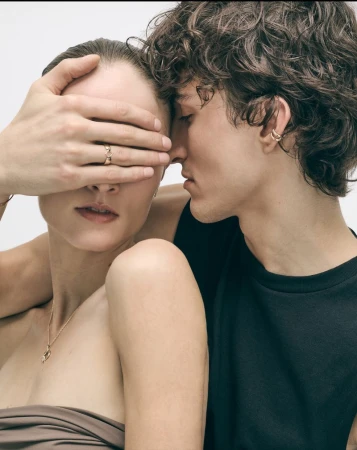 Close-up of a romantic couple in a studio, a woman with hand over her eyes next to a man in a tank top, neutral background.