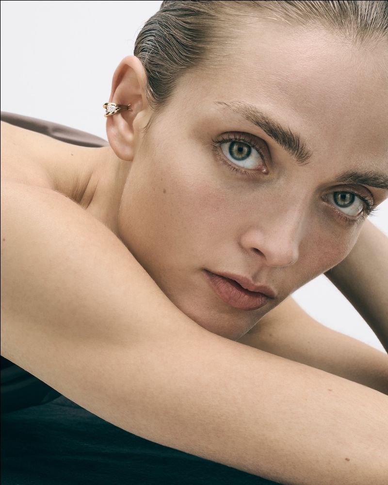 Close-up portrait of an adult woman with ear cuff jewellery, showcasing a clean, modern beauty style with a focus on natural skin texture.