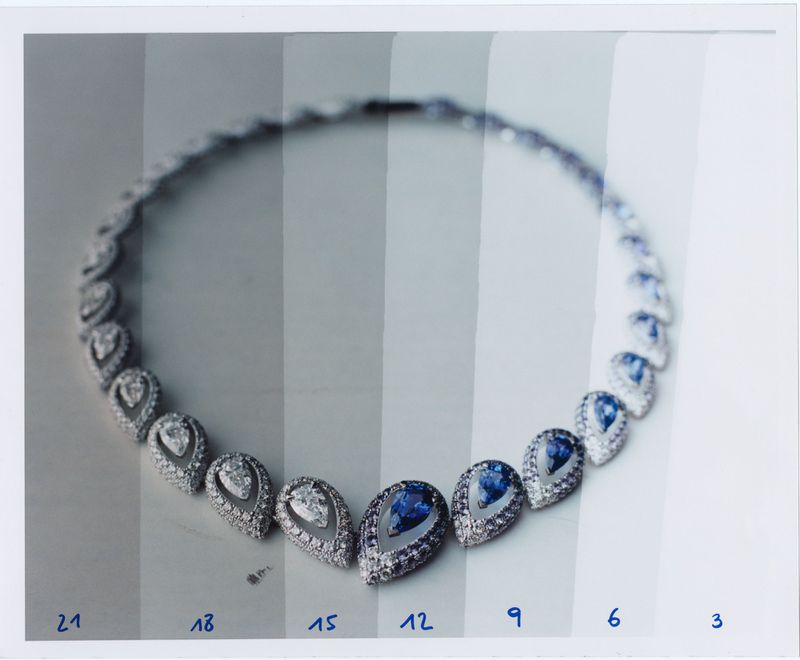 Elegant necklace featuring tear-drop gemstones and diamond halo on a white surface, showcasing jewelry artistry and design.
