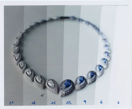 Elegant necklace featuring tear-drop gemstones and diamond halo on a white surface, showcasing jewelry artistry and design.