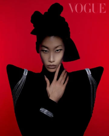 Vogue cover featuring an Asian woman in a black turtleneck and headpiece, adorned with a jeweled shoulder piece and a bracelet, set against a red background.