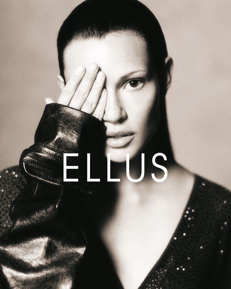 Monochrome portrait of a woman with her hand covering one eye, wearing a v-neck top and jacket, and the word 'ELLUS' overlaid.