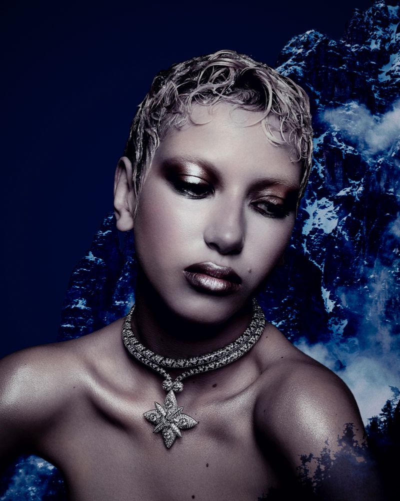 Close-up studio portrait of a young adult woman with a necklace and mountains in the background. Fashion, beauty, and fine art.