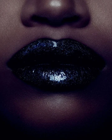 Close-up studio shot of an adult female's glossy, glittery dark blue lips and face. The image showcases cosmetic beauty product.