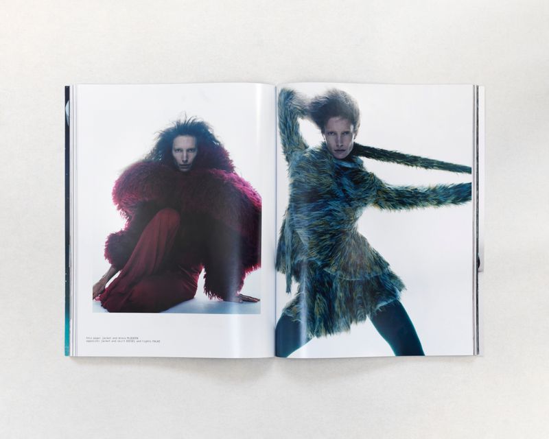Two models on a magazine spread wearing large, textured fur coats. One red and one blue, captured in a photo studio with a white background.