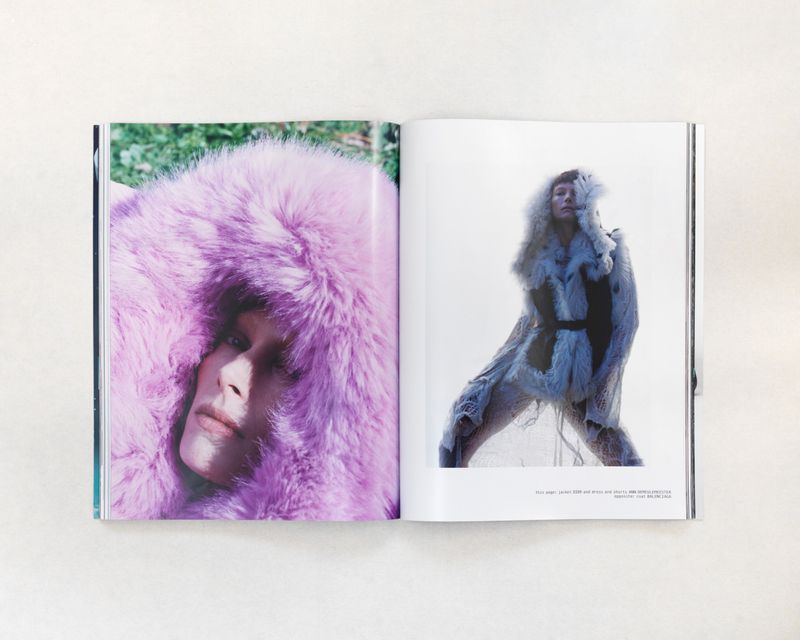 Fashion editorial shot of a woman wearing a lilac faux-fur hooded coat and another woman wearing a white faux-fur ensemble, shot on a magazine spread.