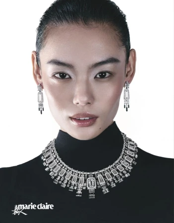 Headshot of an Asian woman with an elegant white and black diamond necklace and earrings, wearing a black turtleneck, against white.