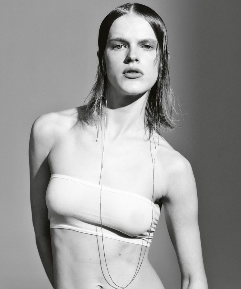 Monochrome portrait of a female model in a strapless top, captured in a photo studio with a grey background, showcasing a fashion editorial style.