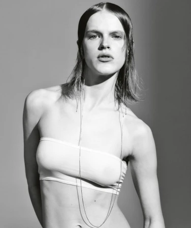 Monochrome portrait of a female model in a strapless top, captured in a photo studio with a grey background, showcasing a fashion editorial style.