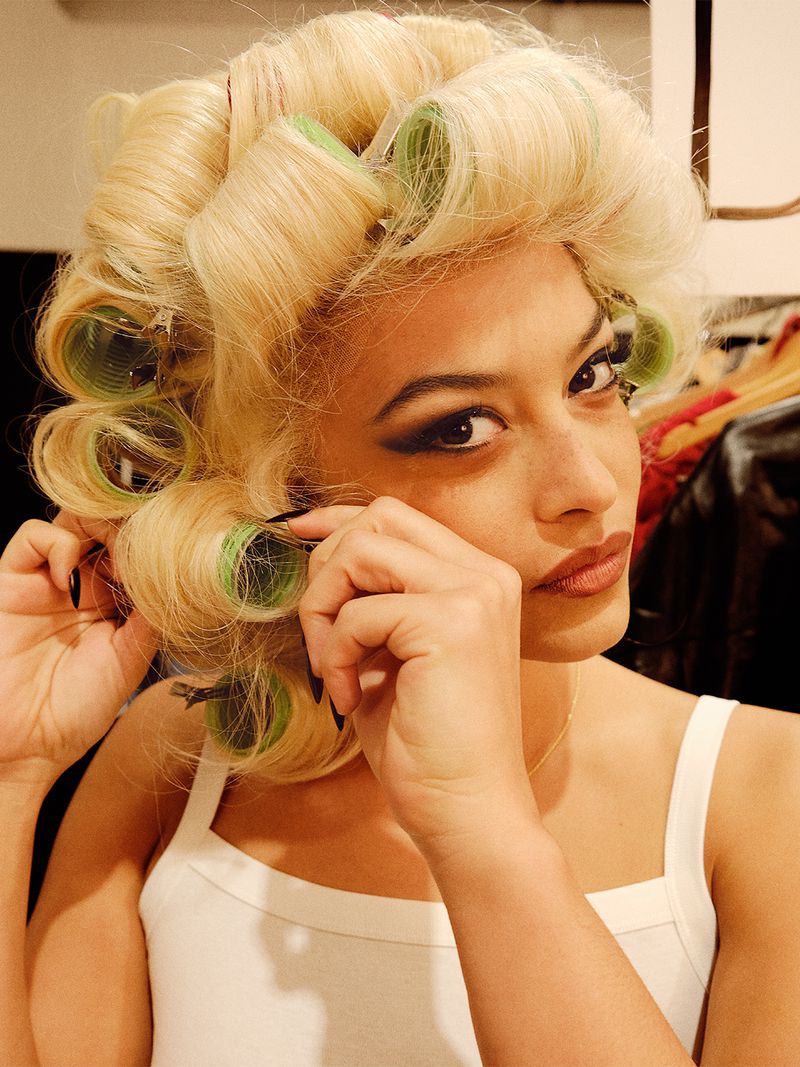 Woman wearing hair rollers. Close-up shot of adult female putting in hair rollers, with blonde hair, dark eyeshadow, and fair complexion.