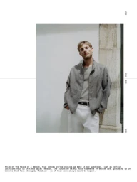 Model leaning against a stone pillar wearing a grey jacket and white trousers for Massimo Dutti