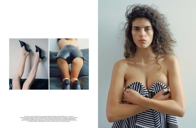 Striking studio shot of a female model with curly hair partially covered by a striped towel, legs in shiny shorts and heels.
