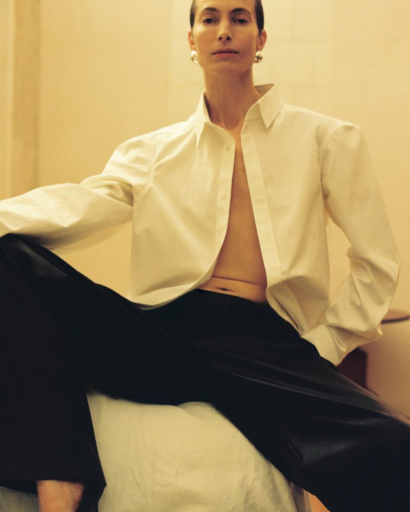 Model Jessica Miller wearing an unbuttoned white shirt and black trousers for Situationist S/S 2026
