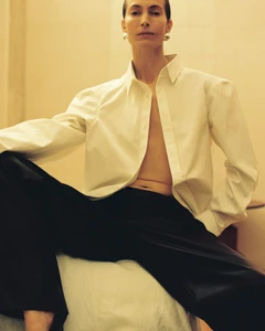 Model Jessica Miller wearing an unbuttoned white shirt and black trousers for Situationist S/S 2026