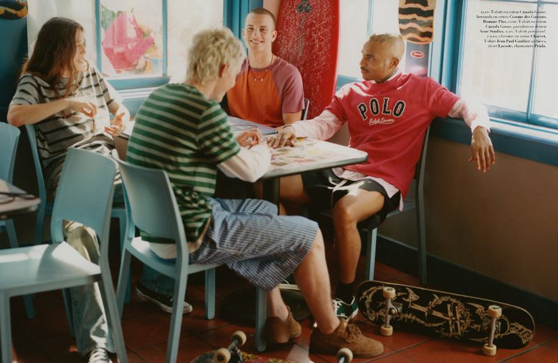 Four people sit at a table in a casual setting, with skateboards nearby, creating a relaxed and youthful atmosphere indoors.