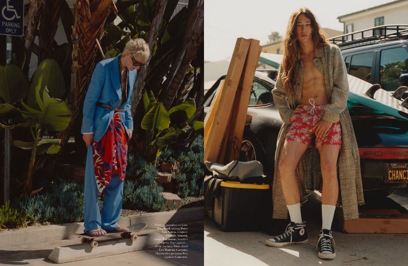 Two fashion models outdoors. One man in blue suit on skateboard. The other shirtless with floral shorts leaning on a car.