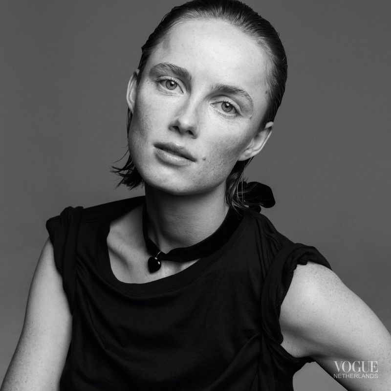 Black-and-white portrait of a young adult woman with short hair, wearing a sleeveless black shirt and necklace against a neutral background.