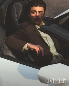A man in a brown jacket seated inside a white sports car, captured in a portrait for L'Officiel Hommes Italia.
