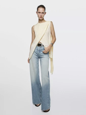 Model wearing a draped cream top and light blue denim jeans against a white seamless background for Massimo Dutti