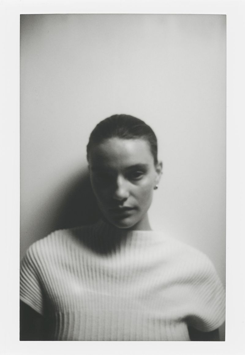 Monochrome portrait of a woman in a ribbed top against a plain background, featuring chiaroscuro lighting and a shallow depth of field.
