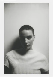 Portrait of a woman wearing a white textured top against a plain light background