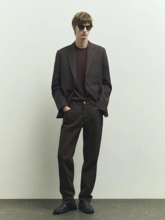Male model wearing a dark blazer, trousers, and sunglasses standing against a seamless background for Massimo Dutti.