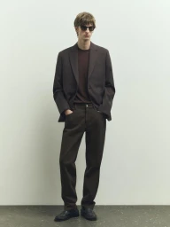 Male model wearing a dark blazer, trousers, and sunglasses standing against a seamless background for Massimo Dutti.