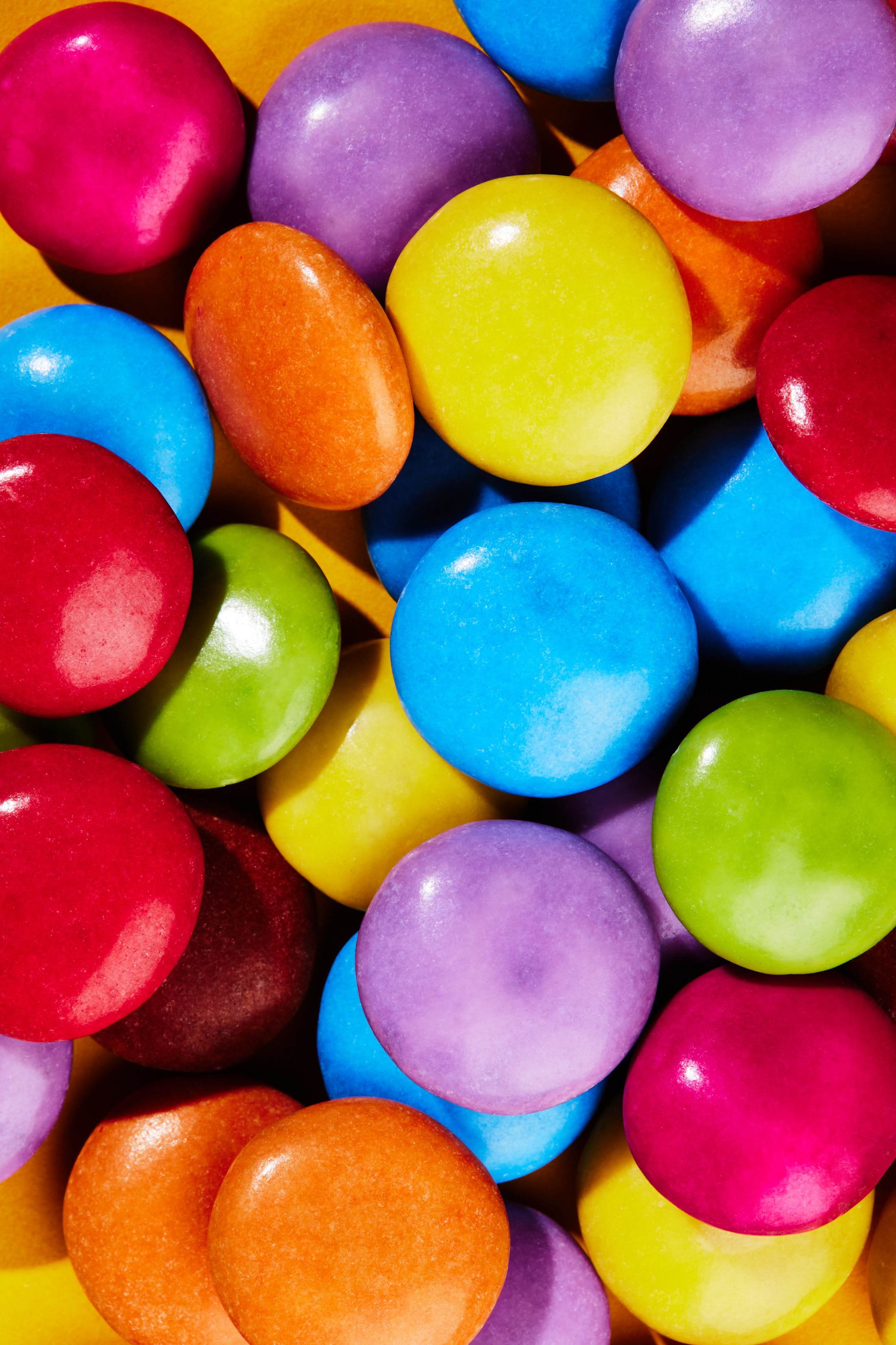 Close-up of colorful candy-coated chocolates in hues of red, orange, yellow, green, blue, and purple creating a vibrant textured food background.