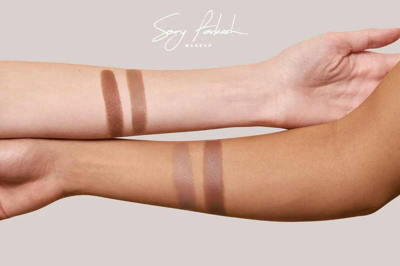 Two forearms demonstrate cosmetic product swatches; one fair-skinned, one tan-skinned, displaying color variation against a neutral backdrop.