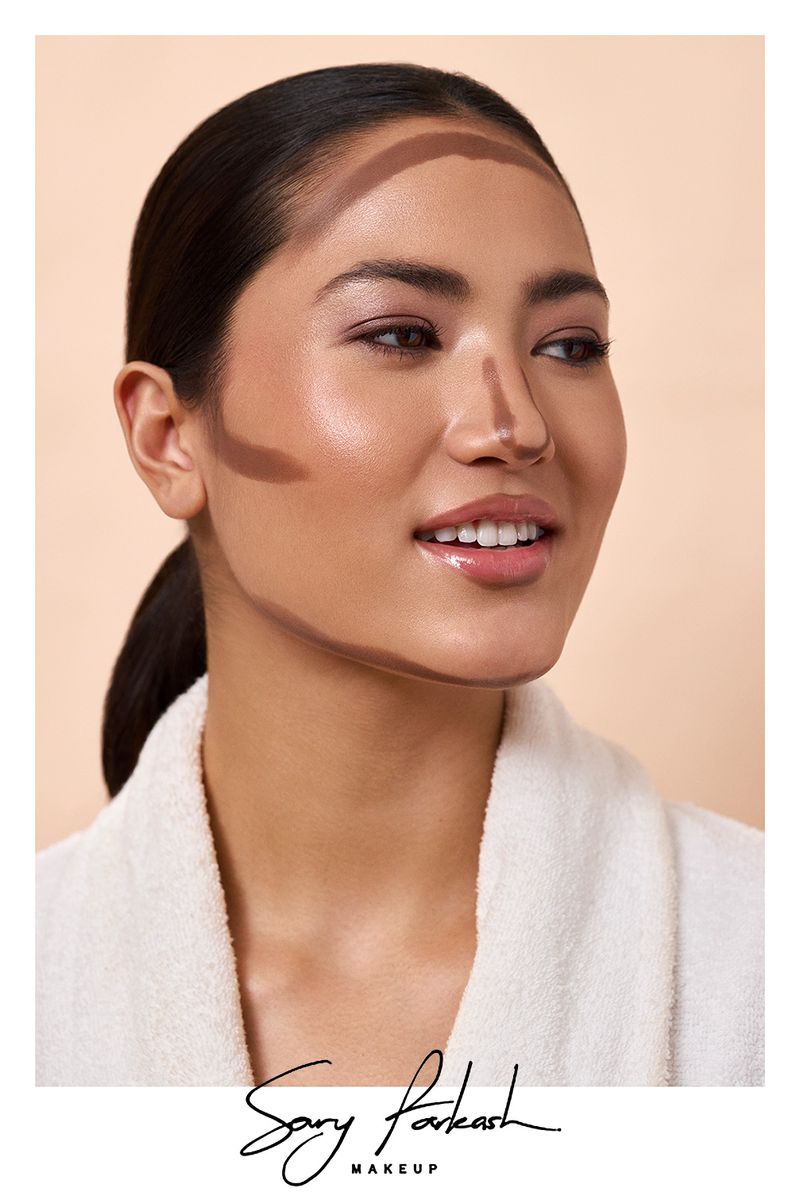 Close-up portrait of an Asian woman with dark hair, wearing a white robe, and light makeup application with contouring on her face.