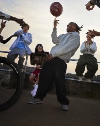 Man spinning a basketball on his finger surrounded by a cheering group in London for Nike
