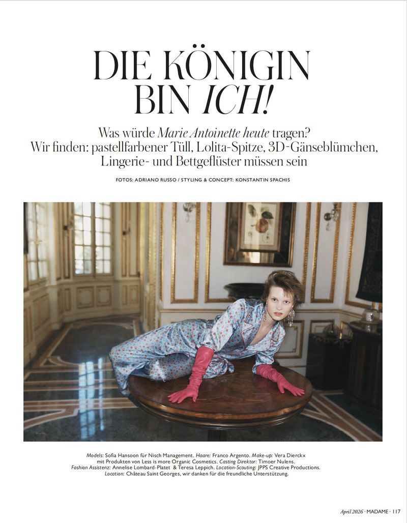 Young woman in loungewear poses on a large wooden table inside a vintage-style room with pink gloves, captured in a fashion editorial style.